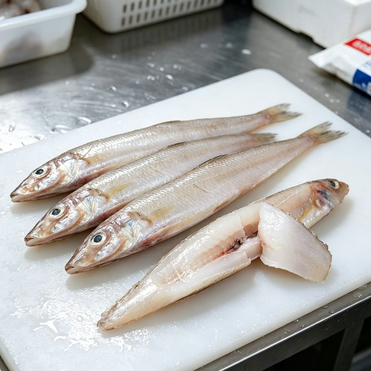 Slender silver sea smelt on a white board with a fillet